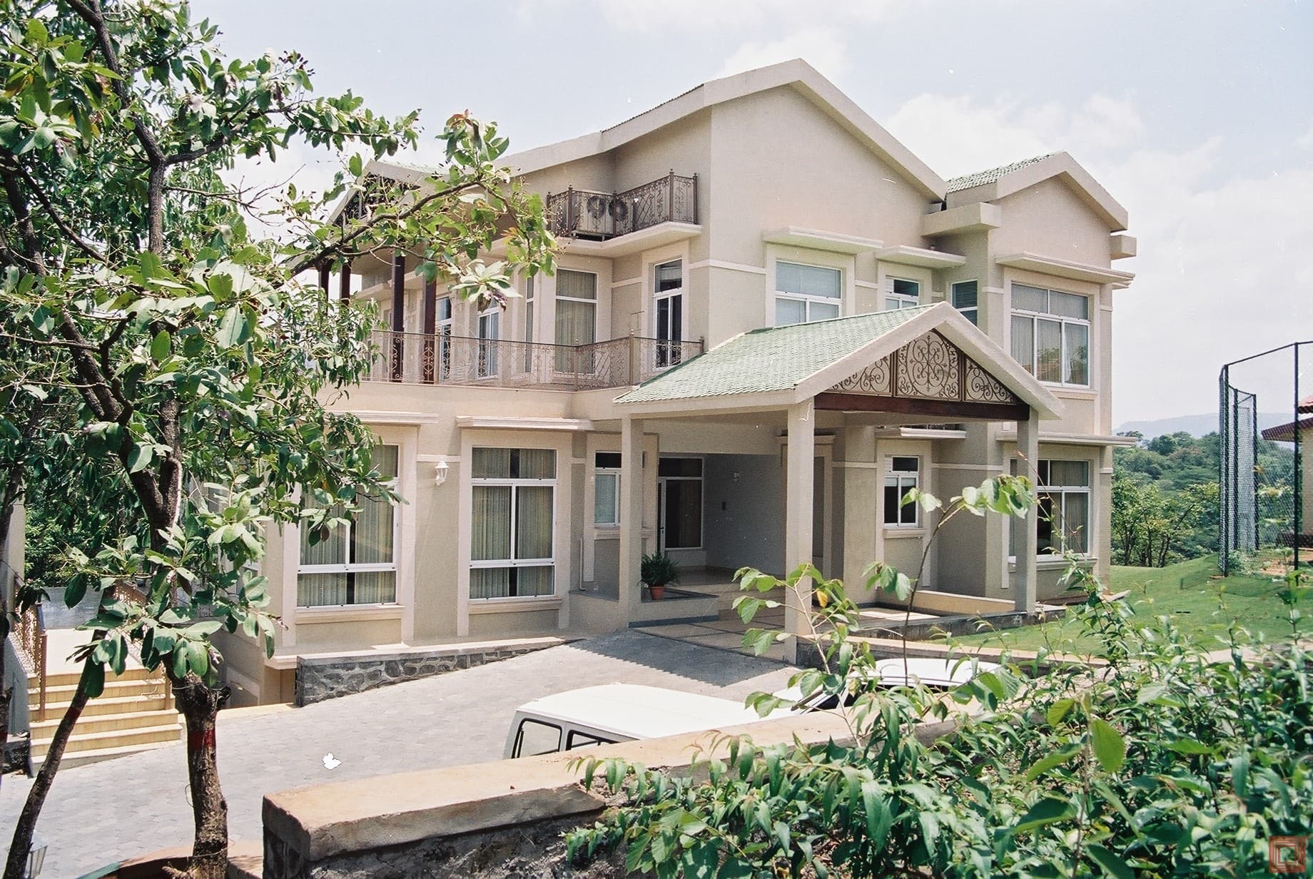 Completed residential bungalow with pitched roofs, balconies, and a covered entrance
